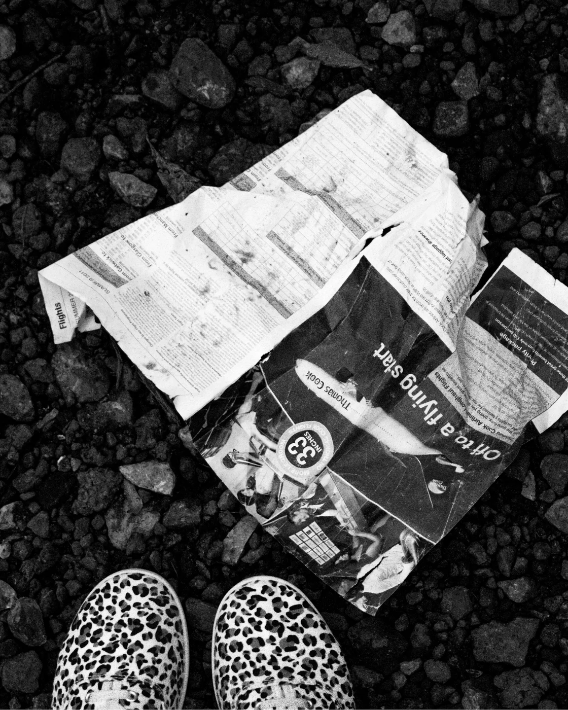 Black-and-white photograph of discarded printed pages among stones